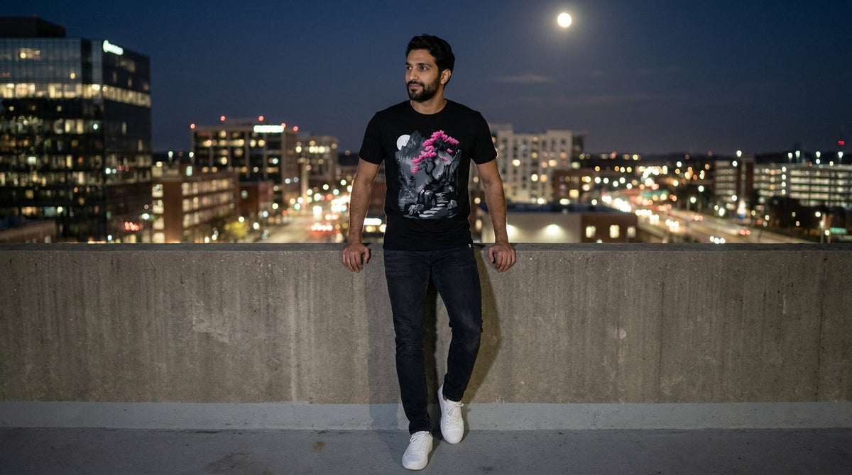 Man in the black Midnight Ascent graphic tee on a city rooftop at night