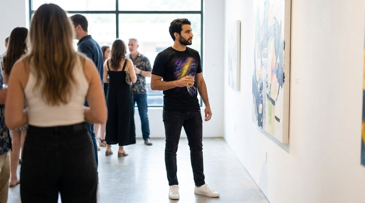 Man in the Celestial Peak graphic tee looking at a painting at a gallery opening