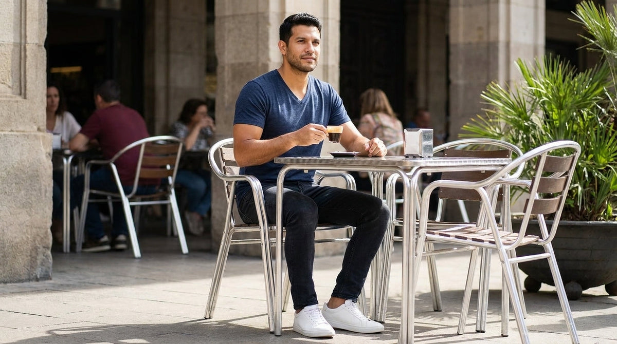 Man in a navy v-neck tee sitting with an espresso at an outdoor cafe table