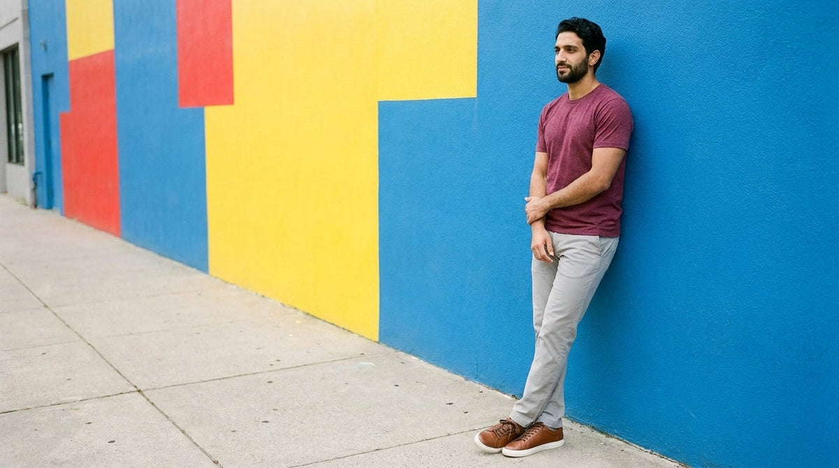 Man in a plain maroon tee against a colour-blocked wall