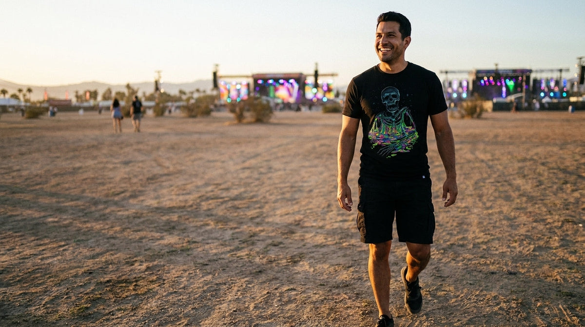Man in an INTO THE AM graphic tee walking across a desert festival field at dusk