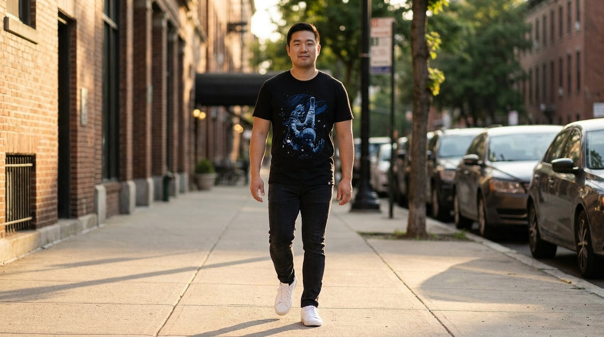 Man in the Cosmic Descent graphic tee walking down a city sidewalk at golden hour